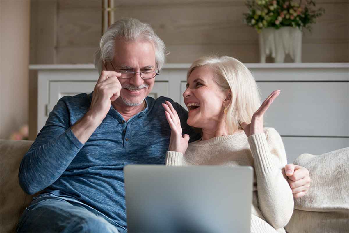 Foto: Zwei Pensionisten sitzen auf einer Couch mit einem Laptop